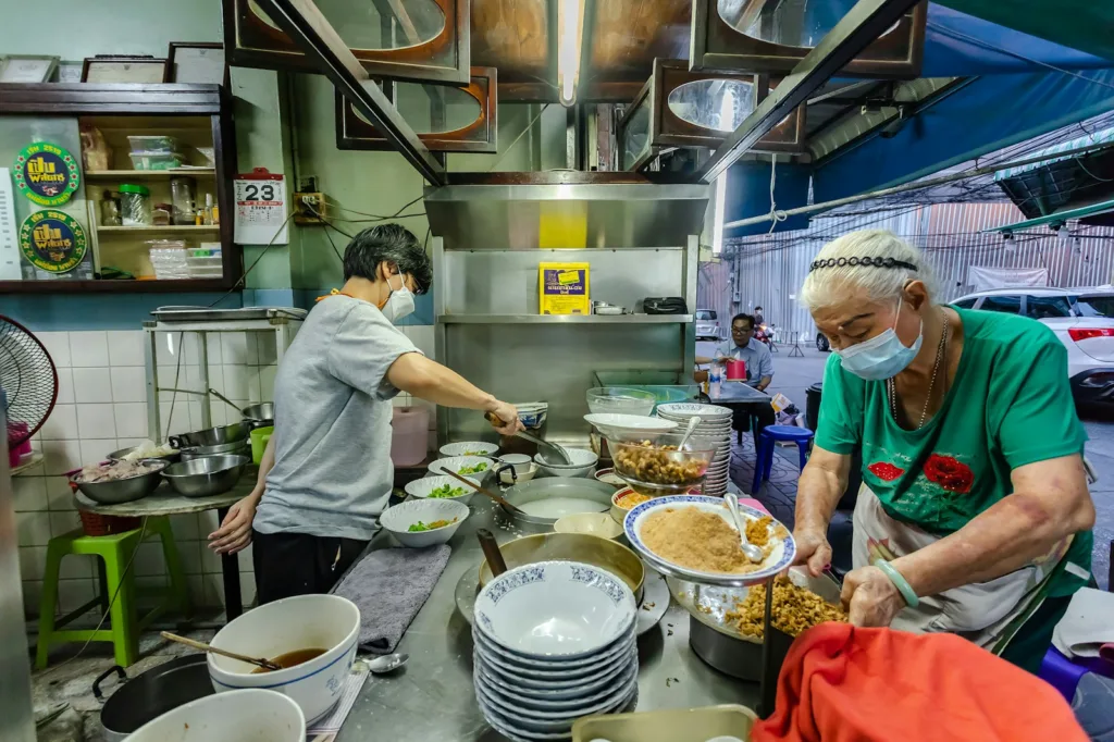 man in white t-shirt and red apron cooking food